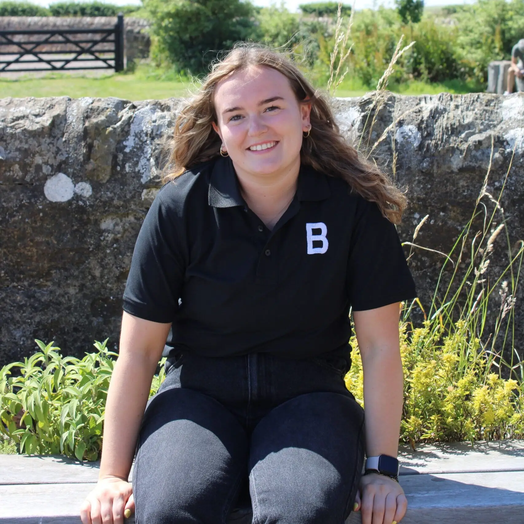 Emma Hamilton, Bowhouse team Emma Hamilton of the Bowhouse team, smiling and sitting on a stone wall